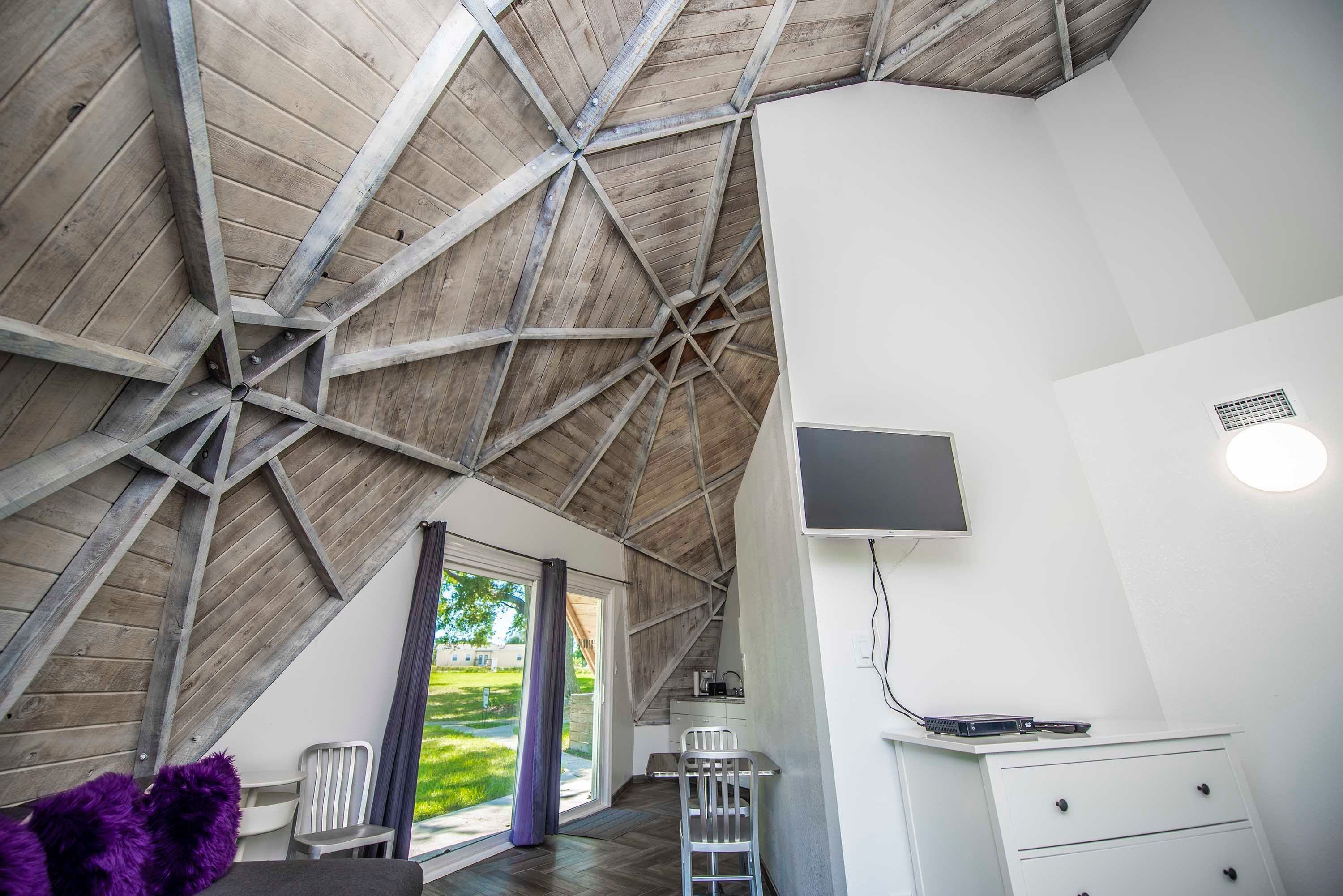 Une pièce avec un plafond en pente, un téléviseur fixé au mur et un bureau avec des tiroirs.