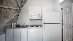 A kitchen with white cabinets, a microwave, a stove, and a refrigerator. - Studio 02 - Lake Sumner (Clermont)