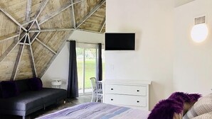 A bedroom with a sloped ceiling, a bed, a dresser, and a television. - Studio 02 - Lake Sumner (Clermont)