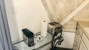 A kitchenette with a coffee maker, toaster, and a roll of paper towels on a glass-top table. - Studio 05 - Lake Sumner (Clermont)