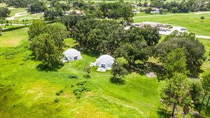 An aerial view of a golf course with two dome-shaped buildings surrounded by lush greenery. - Studio 05 - Lake Sumner (Clermont)