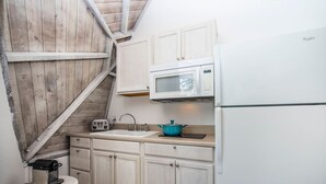 A compact kitchen with white cabinets, a microwave, a sink, and a blue pot on the countertop. - Studio 05 - Lake Sumner (Clermont)