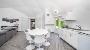 A modern kitchen with white cabinetry, a round dining table with white chairs, and a grey herringbone floor. - Sumner Lake Tiny House - Lake Sumner (Clermont)