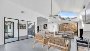 A spacious living area with a high ceiling, a ceiling fan, and a stone wall fireplace. - Swiss 06 - Lake Sumner (Clermont)