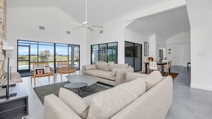 A spacious living room with a large sofa, a coffee table, and a dining area with chairs and a table. - Swiss 06 - Lake Sumner (Clermont)