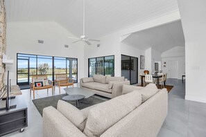 Uma sala de estar ampla com um sofá grande, uma mesa de centro e um espaço de jantar com cadeiras e mesa.