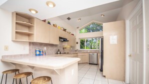 A modern kitchen with a central island, bar stools, and a large window providing natural light. - Swiss 101 - Lake Olsen (Clermont)