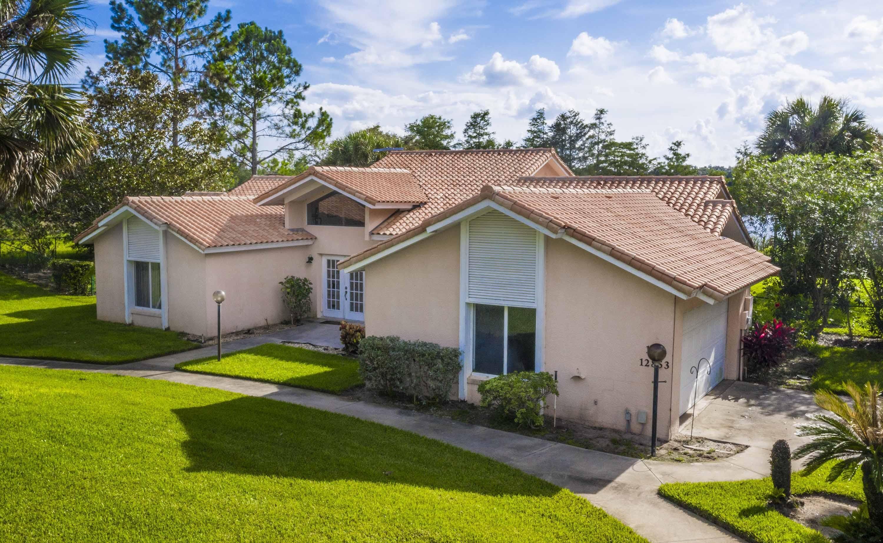 A two-story house with a tiled roof, a front porch, and a well-maintained lawn.