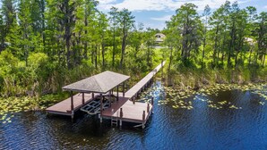 A wooden dock extending into a body of water surrounded by dense greenery and trees. - Swiss 105 - Lake Olsen (Clermont)