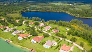 An aerial view of a residential area with houses, swimming pools, and a large lake. - Swiss 105 - Lake Olsen (Clermont)