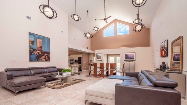 A spacious living area with a sectional sofa, a round coffee table, and a dining area with a high table and chairs. - Swiss 105 - Lake Olsen (Clermont)