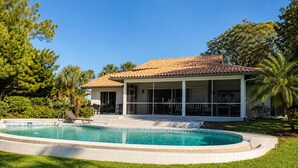 Une maison avec une piscine, un patio couvert et une pelouse.