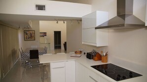 Une cuisine moderne avec des meubles blancs, une cuisinière noire et un coin repas comprenant une table et des chaises.