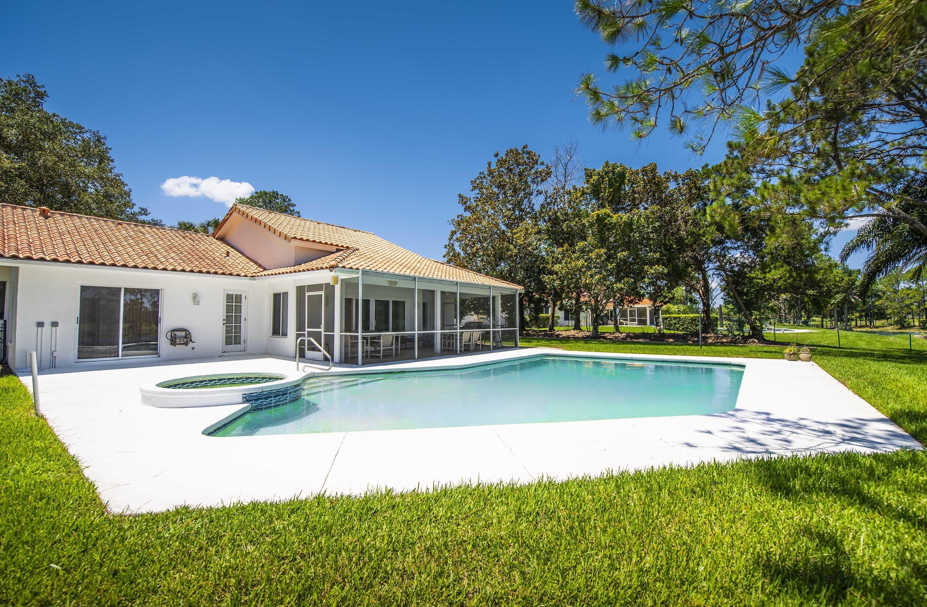 Una casa moderna con piscina, terraza techada y césped bien cuidado.