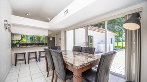A modern kitchen with a marble countertop, black leather chairs, and a large window offering a view of the outdoors. - Swiss 23 - Lake Stephanie (Clermont)