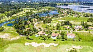 An aerial view of a golf course with multiple water bodies, sand bunkers, and residential areas with houses and swimming pools. - Swiss 31 - Golf Course (Clermont)