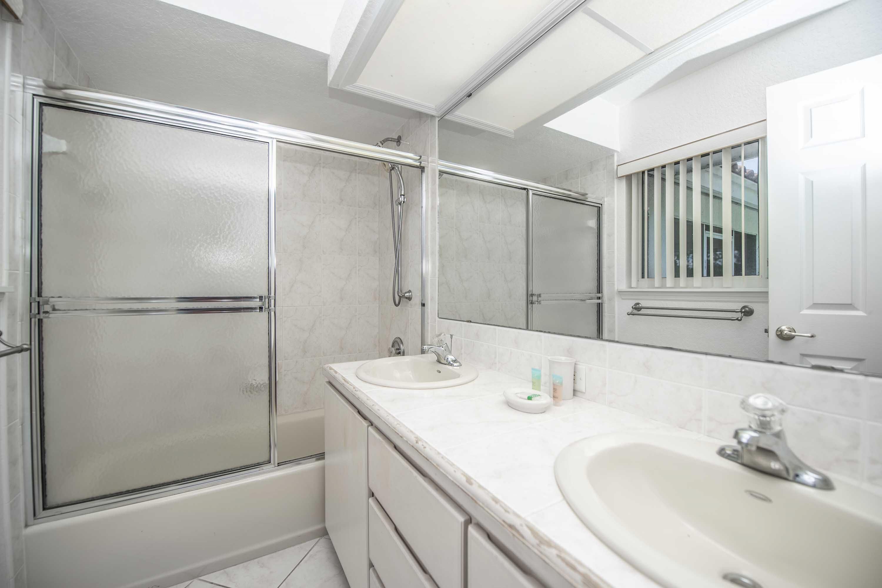 A modern bathroom with a glass shower enclosure, a double sink vanity, and a large mirror.