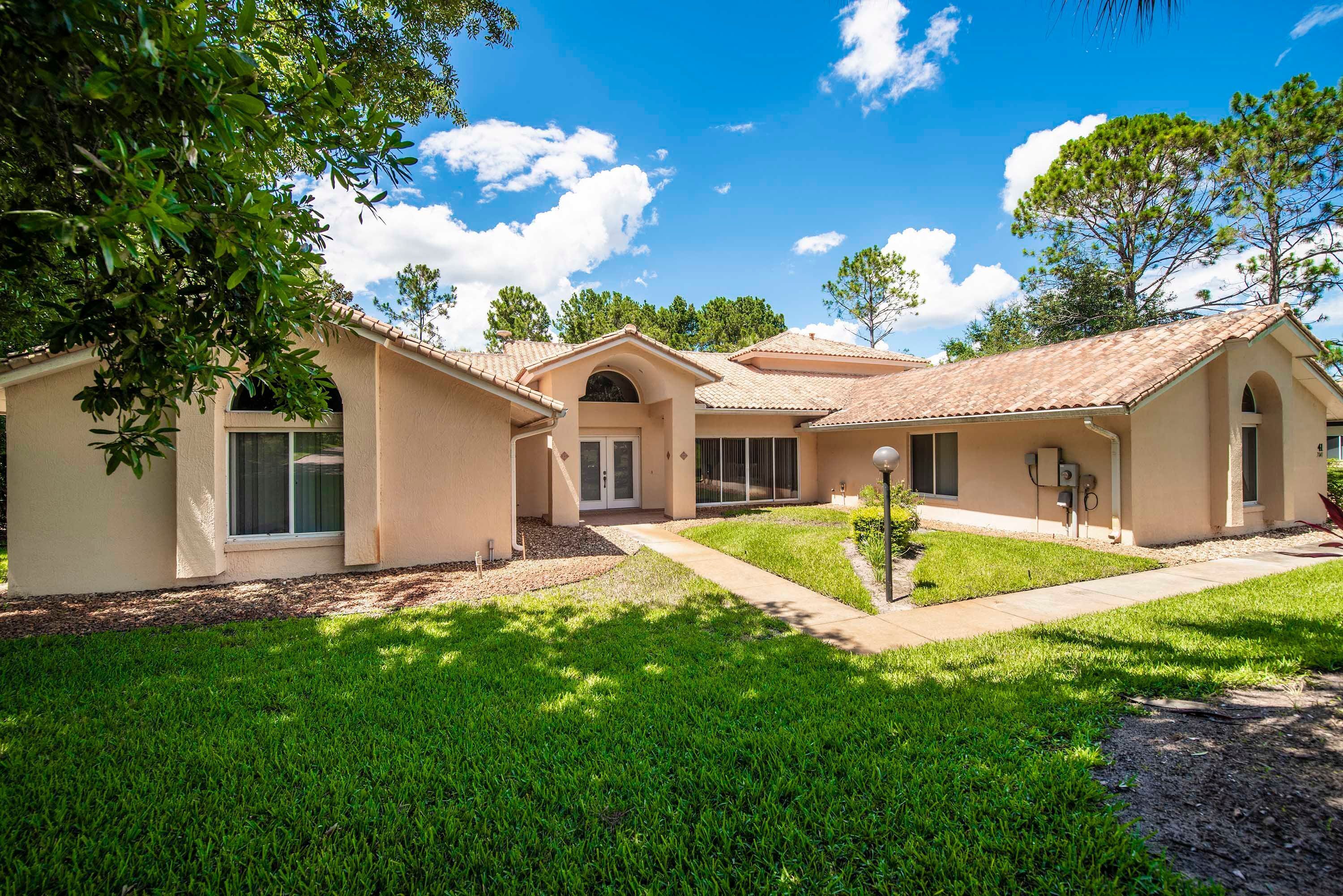 A residential property with multiple houses, a well-maintained lawn, and a clear blue sky.