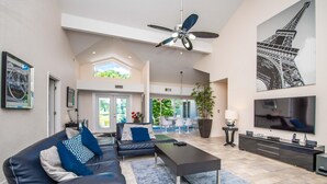Ein geräumiges Wohnzimmer mit einem modernen Sofa, einem Couchtisch und einem Flachbildfernseher.