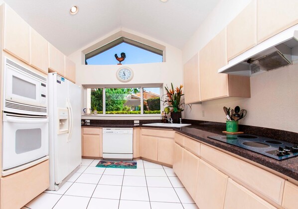 A modern kitchen with white appliances, a window with a view of greenery, and a rooster decoration on the ceiling. - Swiss 61 - Lake Denise (Clermont)