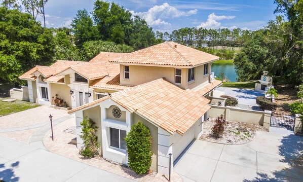 A multi-story house with a tiled roof, a swimming pool, and a well-maintained garden.