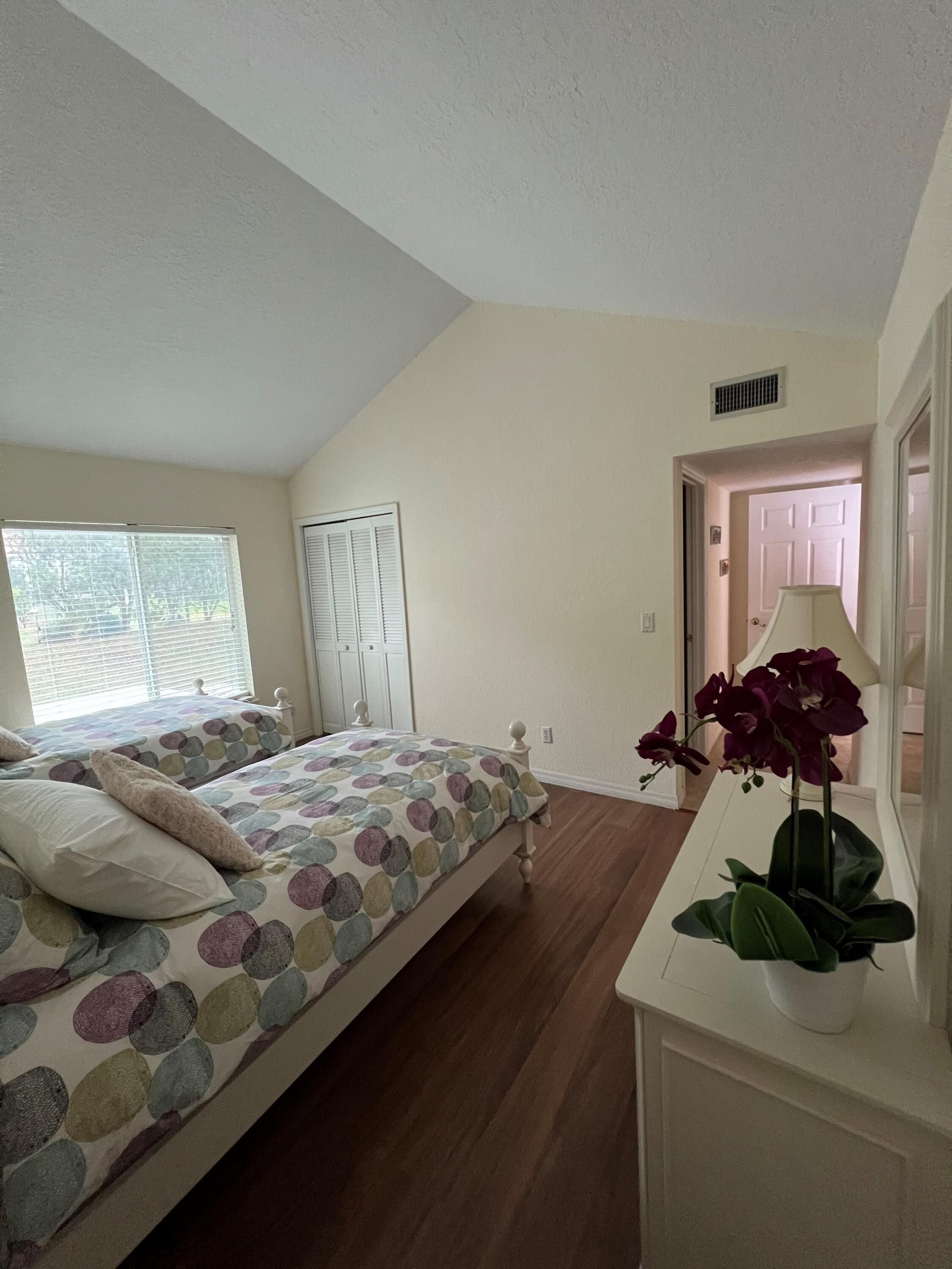 Une chambre à coucher avec un lit, une table de chevet, une fenêtre et une porte.