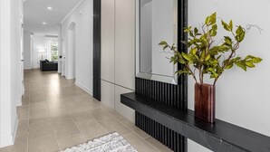 A hallway with a black marble bench, a potted plant, and a large mirror on the wall. - 7 Bedrooms/ 5 Bathrooms/ Champions Gate (8949 PT) (Davenport)