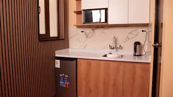 Uma cozinha compacta com geladeira embutida, pia e micro-ondas.
