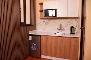 A compact kitchen with a built-in refrigerator, a sink, and a microwave. - Posada Miraflores (Lima)