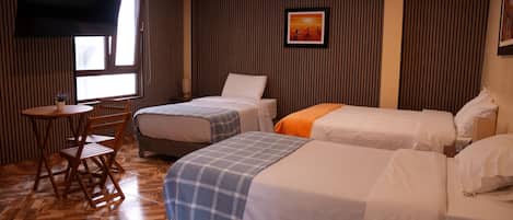 A hotel room with two single beds, a wooden chair, a small table, and a window.