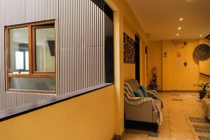 A hallway with a sofa, a clock, and a fire extinguisher. - Posada Miraflores (Lima)