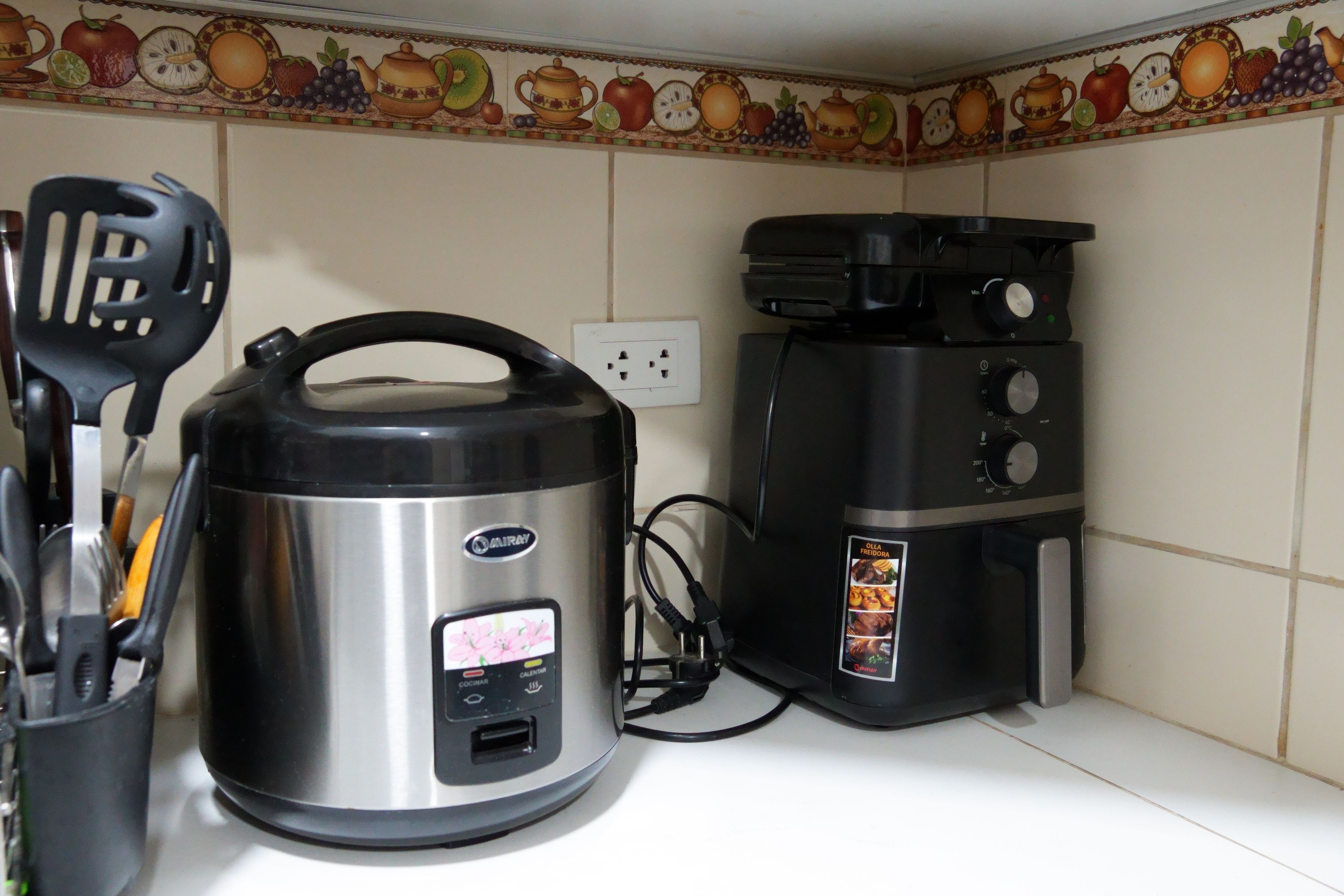A kitchen with a rice cooker, a coffee maker, and a spatula.