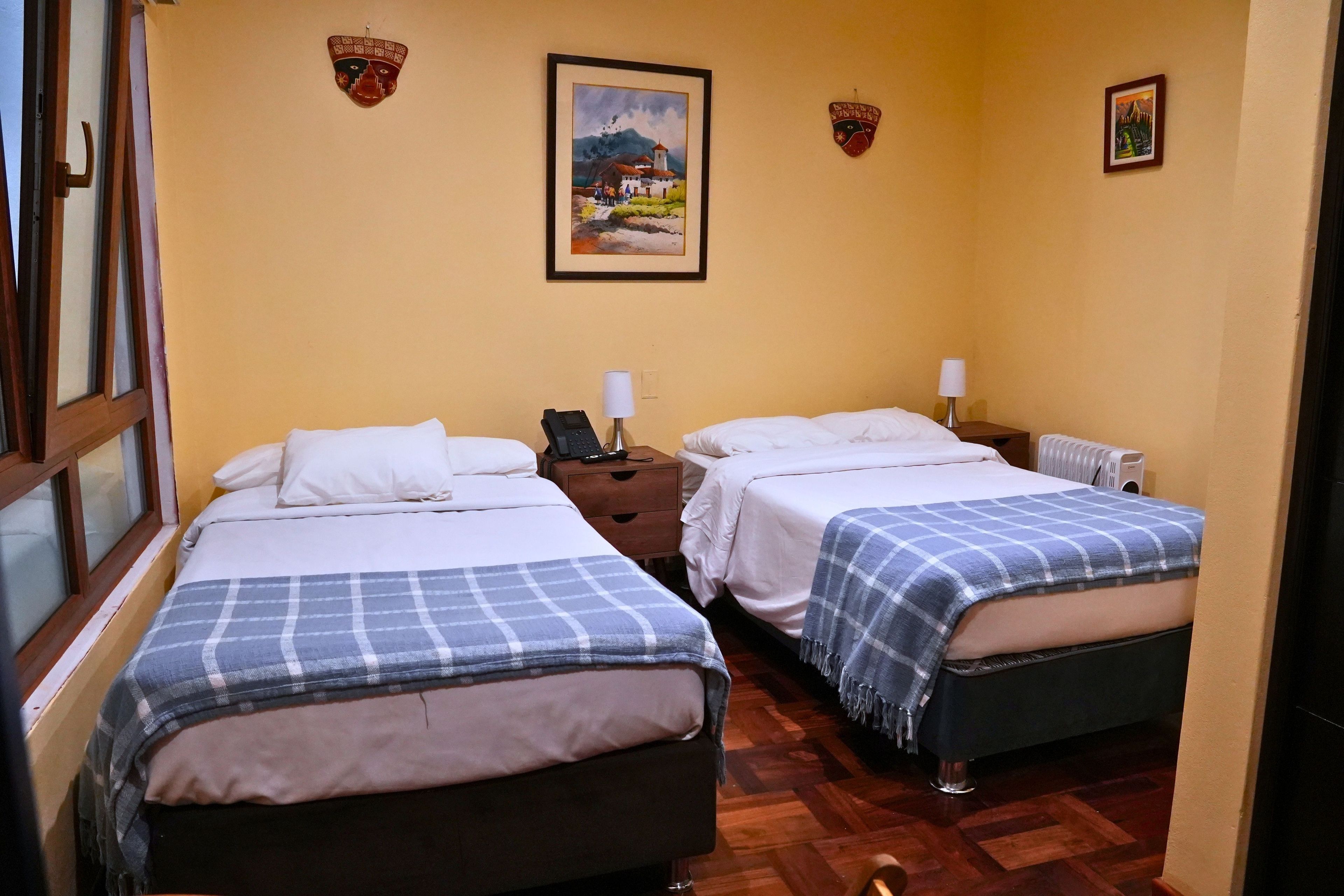 A hotel room with two beds, a wooden floor, a painting on the wall, and a window with a view.
