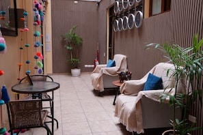 A cozy outdoor seating area with wicker chairs, a round table, and a potted plant. - Posada Miraflores (Lima)