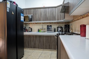 A kitchen with a refrigerator, microwave, stove, and various appliances. - Posada Miraflores (Lima)