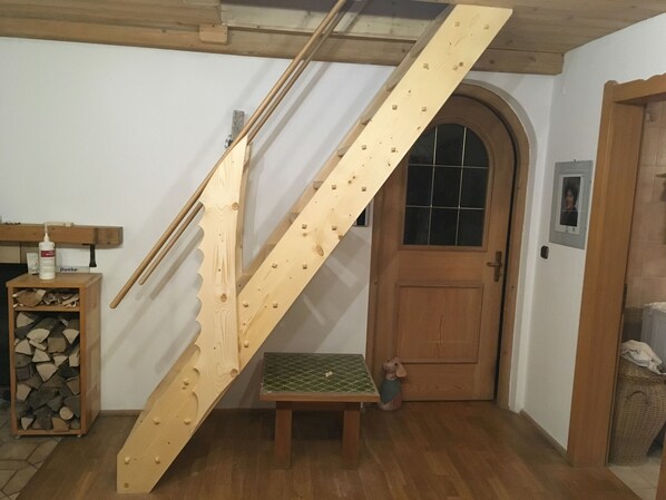 A wooden staircase with a green-tiled landing, a wooden door with a window, and a small wooden bench. - Relaxation on 2 levels; hiking,cycling from the house, skiing in the surrounding (Großweil)