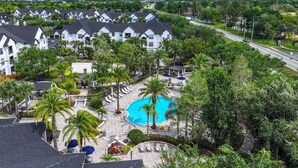 A resort with multiple white buildings, a central swimming pool, and surrounding greenery.