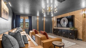A modern living room with a sofa, armchairs, a small table, a TV, and a decorative wall panel. - 7 Bedrooms/ 5 Bathrooms / Champions Gate (1412 TR) (Davenport)