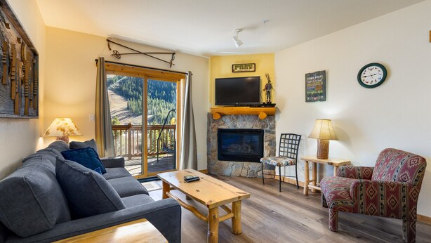 A living room with a stone fireplace, a sofa, a coffee table, and a patterned armchair.