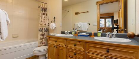 Un bagno con vasca, due lavabi, mobili in legno e un grande specchio.