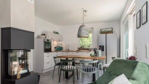 Une cuisine moderne avec des meubles blancs, une table à manger en bois et un fauteuil vert.