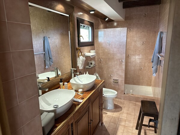 Ein modernes Badezimmer mit zwei Waschbecken, einer Toilette und einer Duschkabine.