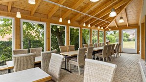 Un restaurante con vigas de madera, muebles de mimbre y ventanas amplias.