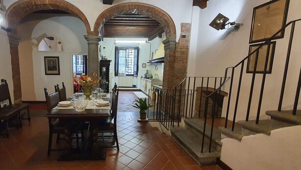 Comedor con una mesa dispuesta para cuatro personas, flanqueado por dos arcos y una escalera.
