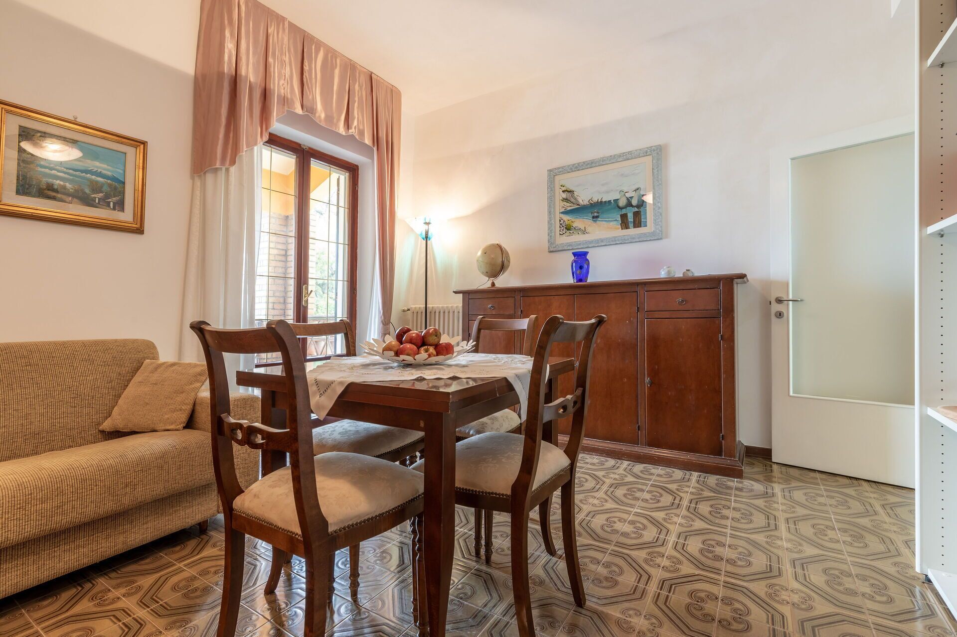 A dining area with a wooden table, four chairs, a sofa, and a cabinet.