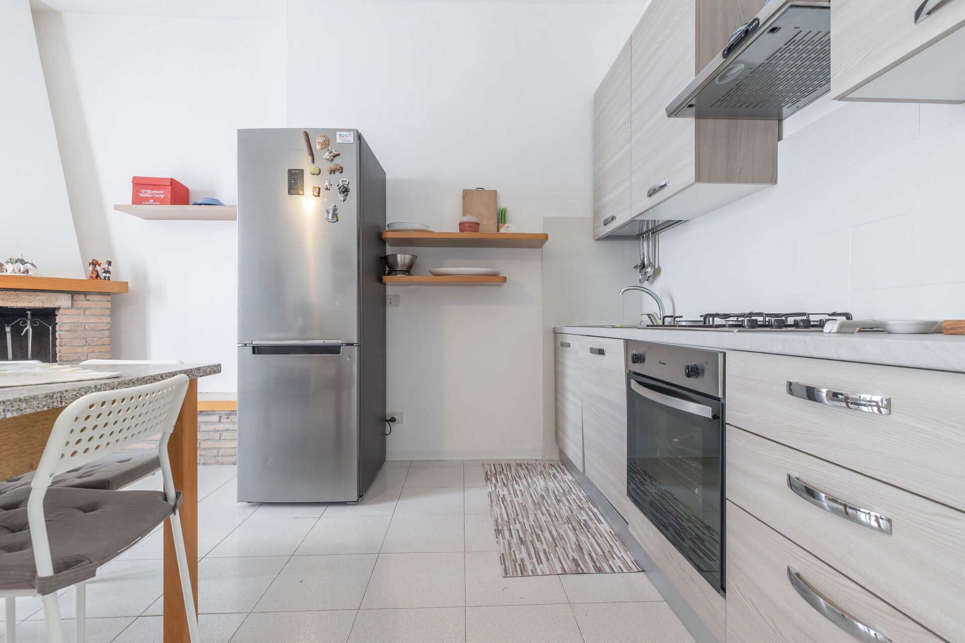 Une cuisine moderne dotée d’un réfrigérateur en acier inoxydable, d’un four encastré et de meubles de rangement en bois.