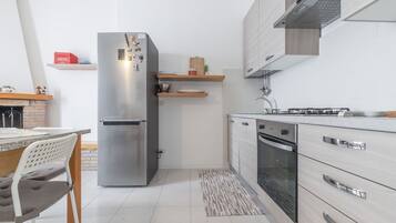 Une cuisine moderne dotée d’un réfrigérateur en acier inoxydable, d’un four encastré et de meubles de rangement en bois.