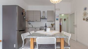 Eine moderne Küche mit einer Granit-Arbeitsplatte, weißen Stühlen und einem Edelstahl-Kühlschrank.