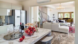 A modern kitchen with marble countertops, a dining area with a marble table, and a living room with a sofa and a chandelier. - Wonderful private villa for 10 people with private pool, A/C, WIFI, TV, terrace and panoramic view (Capo D'orlando)