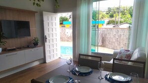 A dining area with a table set for four, a TV mounted on the wall, and a view of the outside. - Blumen Espaço (Blumenau)